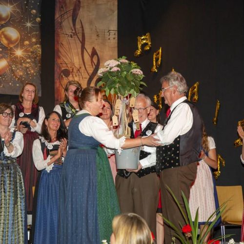 Richard Pertl überreicht Eva-Maria Scherzer die goldene Stimmgabel gratulieren einander während des Jubiläumskonzerts auf der Bühne.