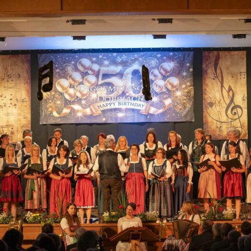 Der gesamte Chor singt unter der Leitung des Dirigenten auf der Bühne im Stadtsaal Radenthein.